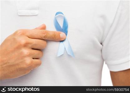 medicine, health care, gesture and people concept - close up of male hand pointing to blue prostate cancer awareness ribbon on his chest