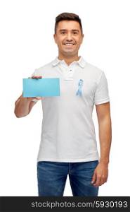medicine, health care, gesture and people concept - middle aged latin man in t-shirt with sky blue prostate cancer awareness ribbon holding blank paper card