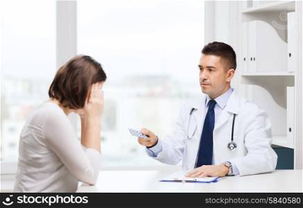 medicine, health care, medication and people concept - doctor with clipboard giving pills to young woman at hospital