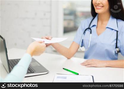 medicine, health care, meeting and people concept - close up of female doctor with laptop computer giving prescription to patient at hospital