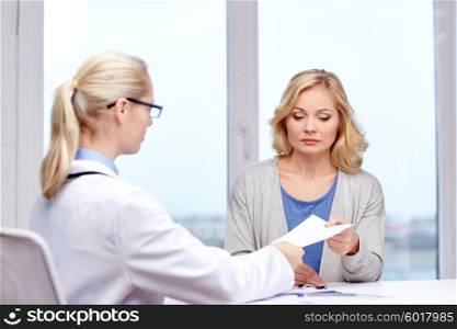 medicine, health care, meeting and people concept - doctor giving medical prescription or certificate to woman at hospital