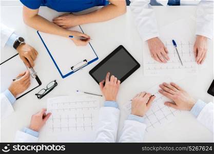 medicine, healthcare and cardiology concept - group of doctors with cardiograms, clipboard and tablet pc computer at hospital. doctors with cardiograms and tablet pc at hospital