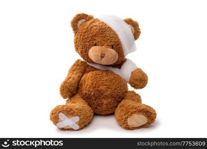 medicine, healthcare and childhood concept - teddy bear toy with bandaged head and paw on white background. teddy bear toy with bandaged head and paw
