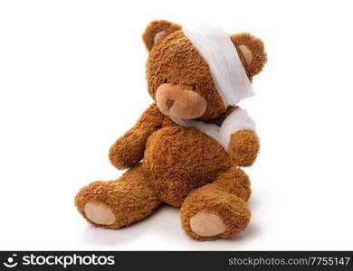 medicine, healthcare and childhood concept - teddy bear toy with bandaged head and paw on white background. teddy bear toy with bandaged head and paw