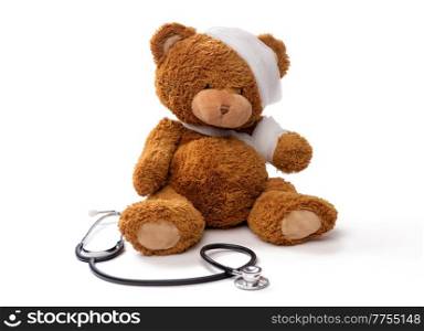 medicine, healthcare and childhood concept - teddy bear toy with bandaged head and paw and stethoscope on white background. bandaged teddy bear toy with stethoscope