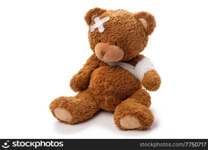 medicine, healthcare and childhood concept - teddy bear toy with bandaged paw and patch on head on white background. teddy bear toy with bandaged paw and patch on head