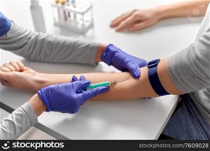 medicine, healthcare and diabetes concept - close up of doctor in gloves with syringe taking blood for test from patient&rsquo;s hand at hospital. doctor taking blood for test from patient&rsquo;s hand