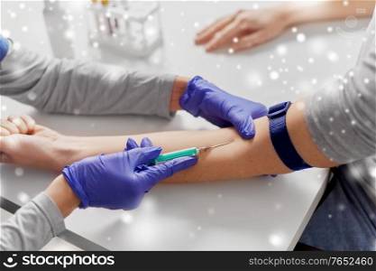 medicine, healthcare and diabetes concept - close up of doctor in gloves with syringe taking blood for test from patient&rsquo;s hand at hospital in winter over snow. doctor taking blood for test from patient&rsquo;s hand