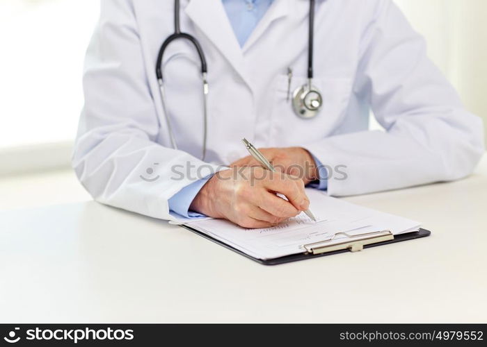 medicine, healthcare and diagnosis people concept - senior doctor with clipboard writing medical report at hospital. senior doctor with clipboard writing at hospital