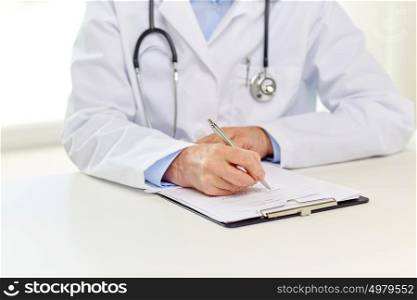 medicine, healthcare and diagnosis people concept - senior doctor with clipboard writing medical report at hospital. senior doctor with clipboard writing at hospital