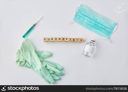 medicine, healthcare and epidemic concept - coronavirus word on wooden toy blocks , protective mask, gloves and syringe with drug on white background. coronavirus word, mask, gloves, syringe and drug