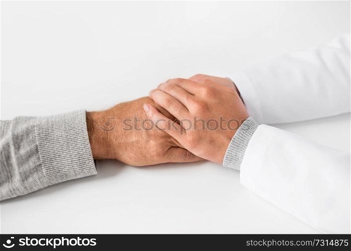 medicine, healthcare and old age concept - close up of young doctor holding senior patient hand. close up of doctor holding senior patient hand