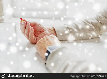 medicine, healthcare and old people concept - close up of senior man hands with pill over snow. close up of old man hands with pill