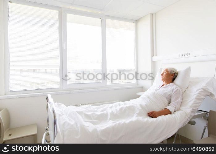 medicine, healthcare and old people concept - sad senior woman lying on bed at hospital ward. sad senior woman lying on bed at hospital ward. sad senior woman lying on bed at hospital ward