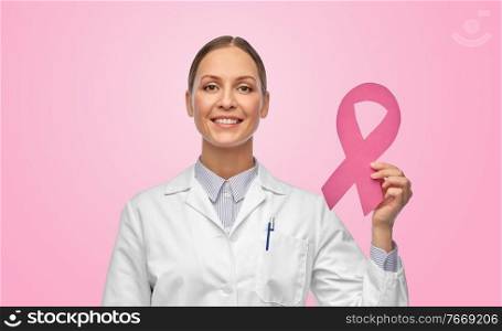 medicine, healthcare and oncology concept - happy smiling female doctor in white coat with breast cancer awareness ribbon over pink background. female doctor with breast cancer awareness ribbon