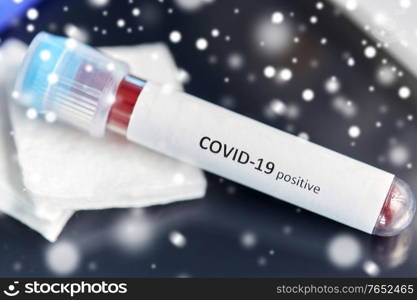 medicine, healthcare and pandemic concept - close up of beaker with positive coronavirus blood test on table at laboratory in winter over snow. beaker with coronavirus blood test at laboratory