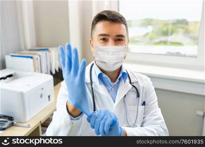 medicine, healthcare and pandemic concept - middle- aged male doctor with stethoscope in medical mask for protection from virus wearing protective gloves at hospital. doctor in medical mask wearing gloves at hospital