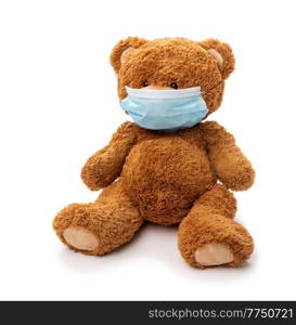 medicine, healthcare and pandemic concept - teddy bear toy in protective medical mask on white background. teddy bear toy in protective medical mask