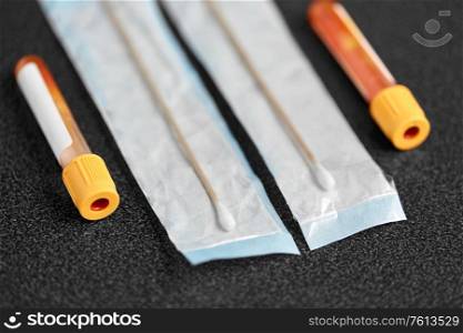 medicine, healthcare and pandemic concept - test tubes with blood plasma and cotton swabs on table. test tubes with blood plasma and cotton swabs
