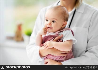 medicine, healthcare and pediatrics concept - close up of female pediatrician doctor or nurse holding baby girl patient at clinic or hospital. female pediatrician doctor with baby at clinic