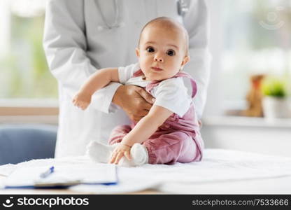 medicine, healthcare and pediatrics concept - female pediatrician doctor or nurse holding baby girl patient at clinic or hospital. female pediatrician doctor with baby at clinic