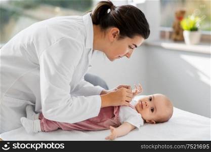 medicine, healthcare and pediatrics concept - female pediatrician doctor with baby girl patient at clinic or hospital. female pediatrician doctor with baby at clinic