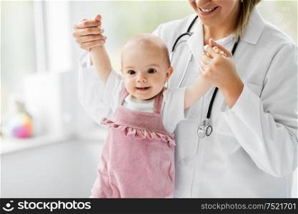 medicine, healthcare and pediatrics concept - female pediatrician or neuropathist doctor or nurse checking smiling baby girl patient&rsquo;s health at clinic or hospital. female pediatrician doctor with baby at clinic