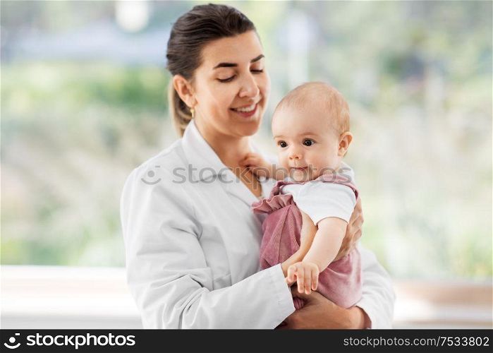 medicine, healthcare and pediatrics concept - smiling female pediatrician doctor or nurse holding baby girl patient at clinic or hospital. female pediatrician doctor with baby at clinic