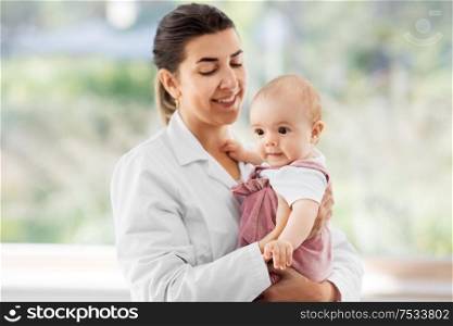 medicine, healthcare and pediatrics concept - smiling female pediatrician doctor or nurse holding baby girl patient at clinic or hospital. female pediatrician doctor with baby at clinic