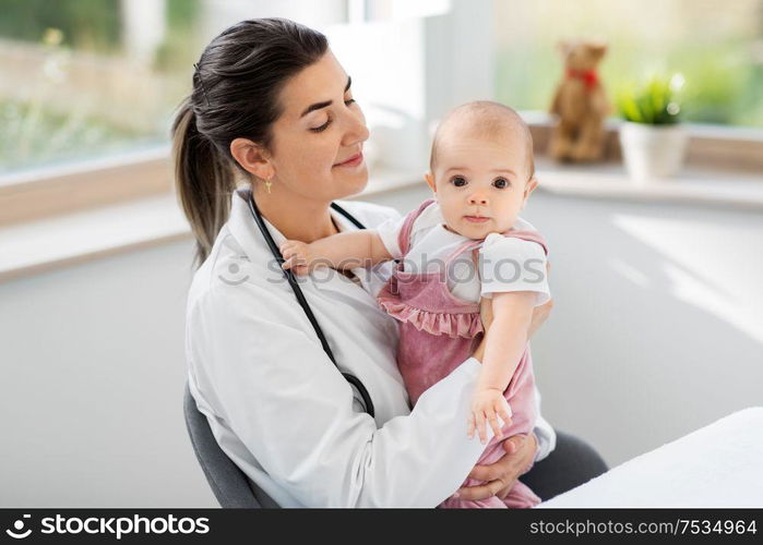 medicine, healthcare and pediatrics concept - smiling female pediatrician doctor or nurse holding baby girl patient at clinic or hospital. female pediatrician doctor with baby at clinic