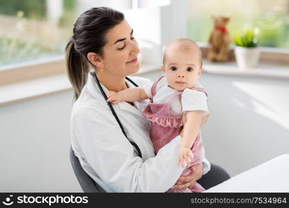 medicine, healthcare and pediatrics concept - smiling female pediatrician doctor or nurse holding baby girl patient at clinic or hospital. female pediatrician doctor with baby at clinic