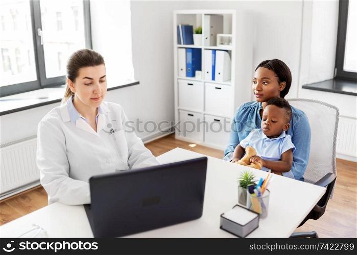 medicine, healthcare and pediatry concept - african american mother with baby son and caucasian doctor with laptop computer at clinic. mother with baby and doctor with laptop at clinic