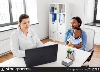 medicine, healthcare and pediatry concept - african american mother with baby son and caucasian doctor with laptop computer at clinic. mother with baby and doctor with laptop at clinic