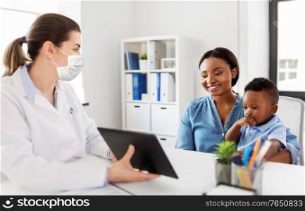 medicine, healthcare and pediatry concept - african american mother with baby son and caucasian doctor wearing protective medical mask for protection from virus disease with tablet computer at clinic. mother, baby and doctor in mask with tablet pc