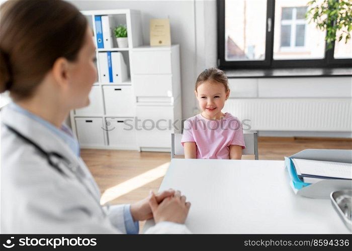 medicine, healthcare and pediatry concept - female doctor or pediatrician talking to happy smiling little girl patient on medical exam at clinic. female doctor and little girl patient at clinic