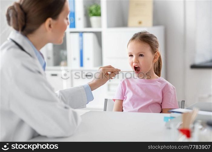 medicine, healthcare and pediatry concept - female doctor or pediatrician with tongue depressor checking little girl patient&rsquo;s throat on medical exam at clinic. female doctor and little girl patient at clinic