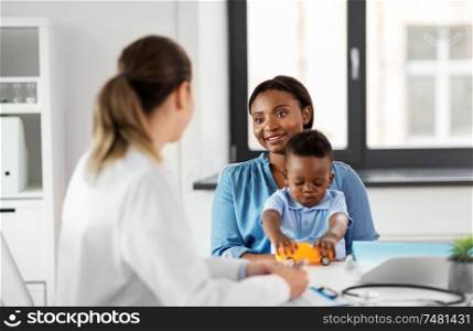medicine, healthcare and pediatry concept - happy african american mother with baby son and caucasian doctor at clinic. happy mother with baby son and doctor at clinic