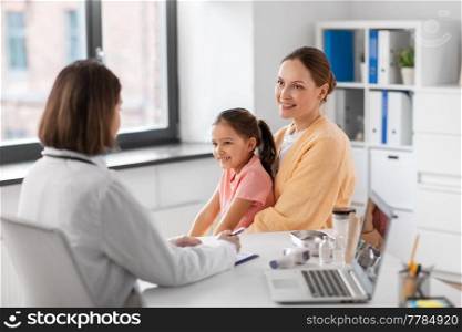 medicine, healthcare and pediatry concept - happy smiling mother with little daughter talking to doctor at clinic. mother with little daughter and doctor at clinic
