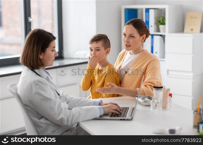 medicine, healthcare and pediatry concept - mother with little coughing son and doctor with laptop computer at clinic. mother, son and doctor with laptop at clinic