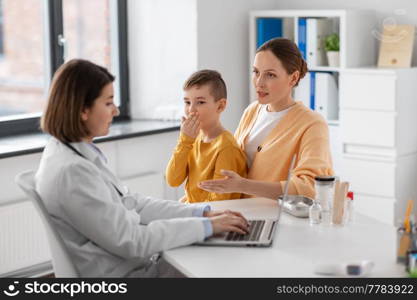 medicine, healthcare and pediatry concept - mother with little coughing son and doctor with laptop computer at clinic. mother, son and doctor with laptop at clinic