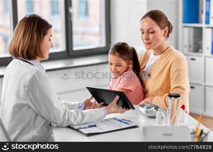 medicine, healthcare and pediatry concept - mother with little daughter and doctor showing tablet pc computer at clinic. mother, child and doctor with tablet pc at clinic