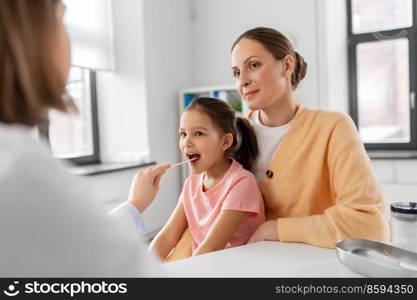 medicine, healthcare and pediatry concept - mother with little daughter and doctor with tongue depressor checking little girl patient’s throat at clinic. female doctor checking girl’s throat at clinic