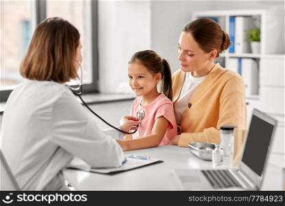 medicine, healthcare and pediatry concept - mother with little daughter and doctor with stethoscope at clinic. mother, girl and doctor with stethoscope at clinic