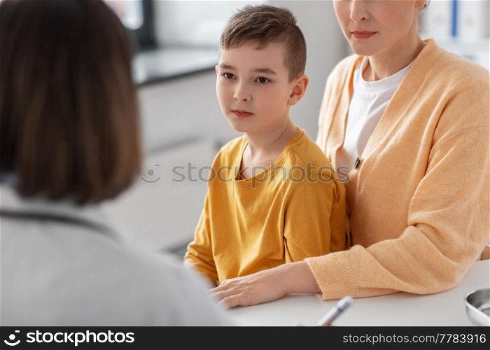 medicine, healthcare and pediatry concept - mother with little son and doctor talking at clinic. mother, son and doctor talking at clinic