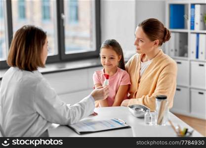 medicine, healthcare and pediatry concept - mother with smiling little daughter and doctor showing them oral spray at clinic. mother, child and doctor with medicine at clinic