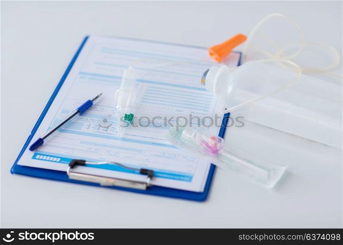 medicine, healthcare and people concept - close up of clipboard with medical report, drop counter and catheter. close up of medical report and drop counter