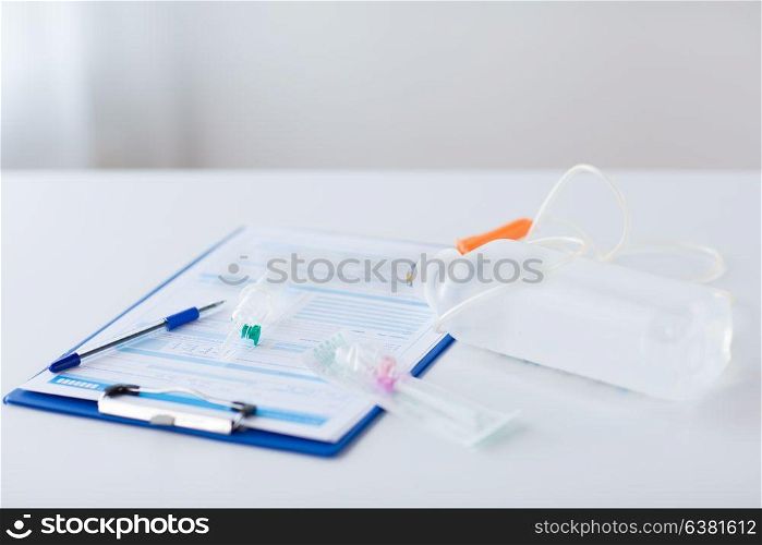medicine, healthcare and people concept - close up of clipboard with medical report, drop counter and catheter on table. close up of medical report and drop counter