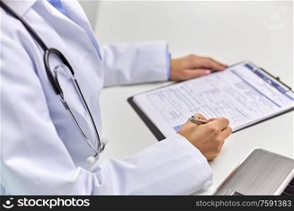 medicine, healthcare and people concept - close up of female doctor writing medical report. close up of female doctor writing medical report