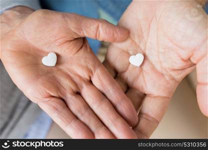 medicine, healthcare and people concept - close up of senior couple hands with heart shaped pills. close up of couple hands with heart shaped pill