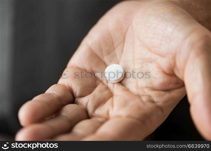 medicine, healthcare and people concept - close up of senior man hand with pill. close up of senior man hand with pill